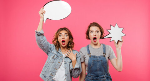 Two shocked ladies friends holding speech bubbles.